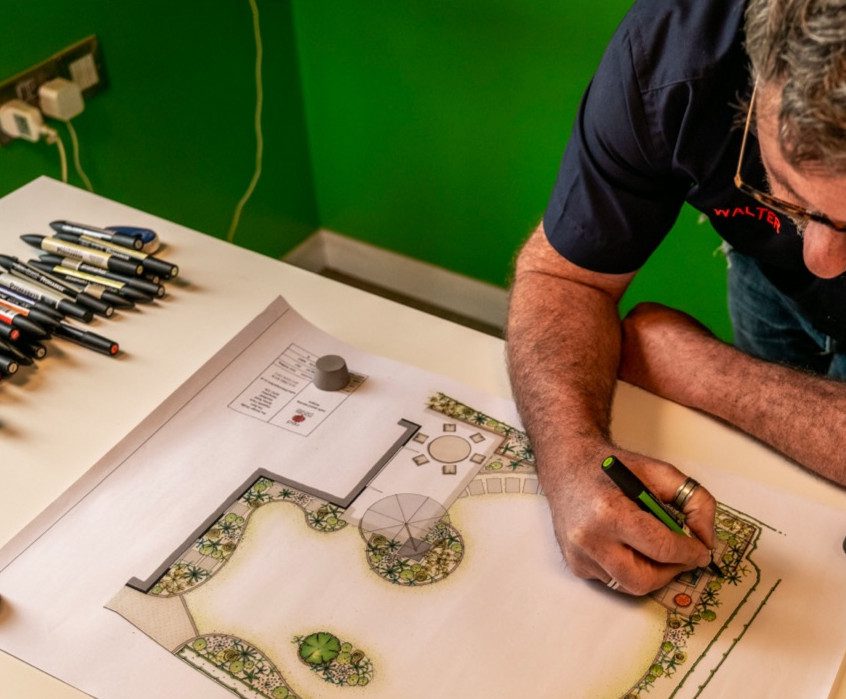 Over the head photo of a landscape gardener drawing a garden design.